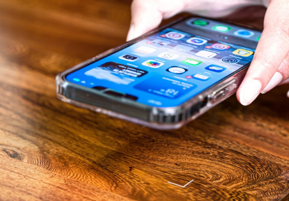 机の上のスマホを取る人